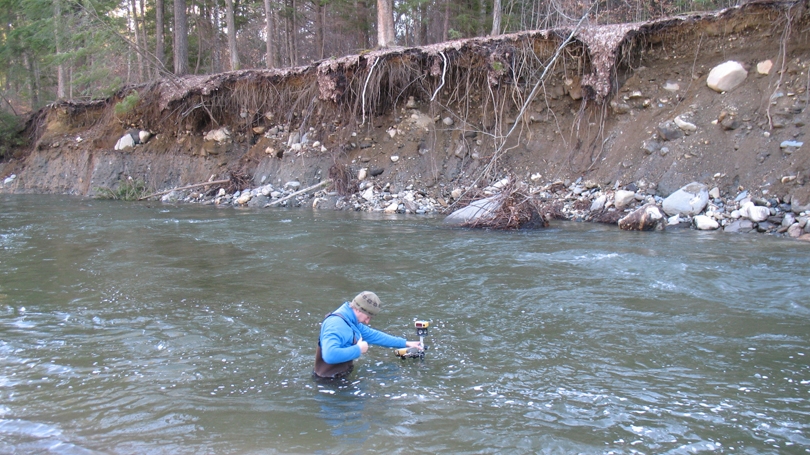 Graduate student surveying the stream channel